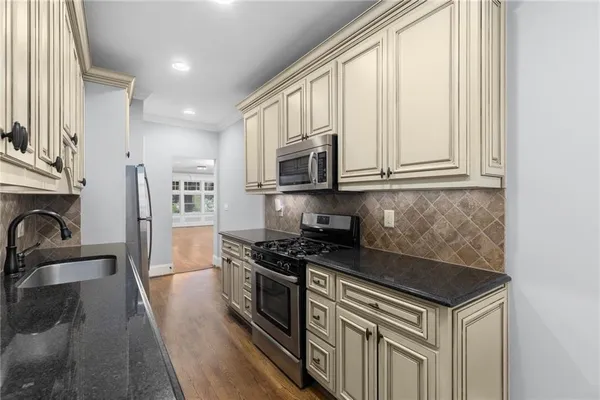 a kitchen with stainless steel appliances granite countertop a stove a sink and a microwave