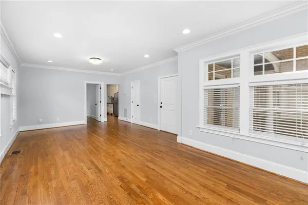 a view of an empty room with wooden floor and a window