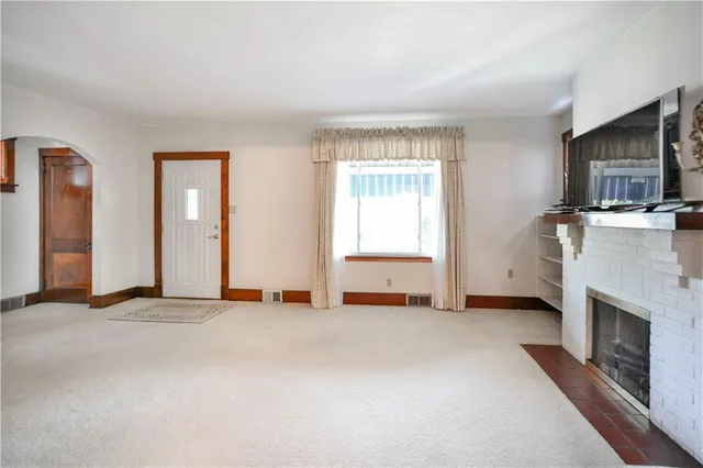 an empty room with windows fireplace and a kitchen counter