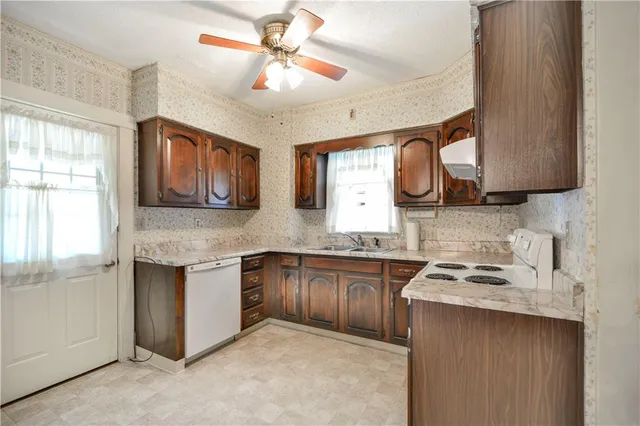 a kitchen with stainless steel appliances granite countertop a sink a stove a refrigerator cabinets and a window