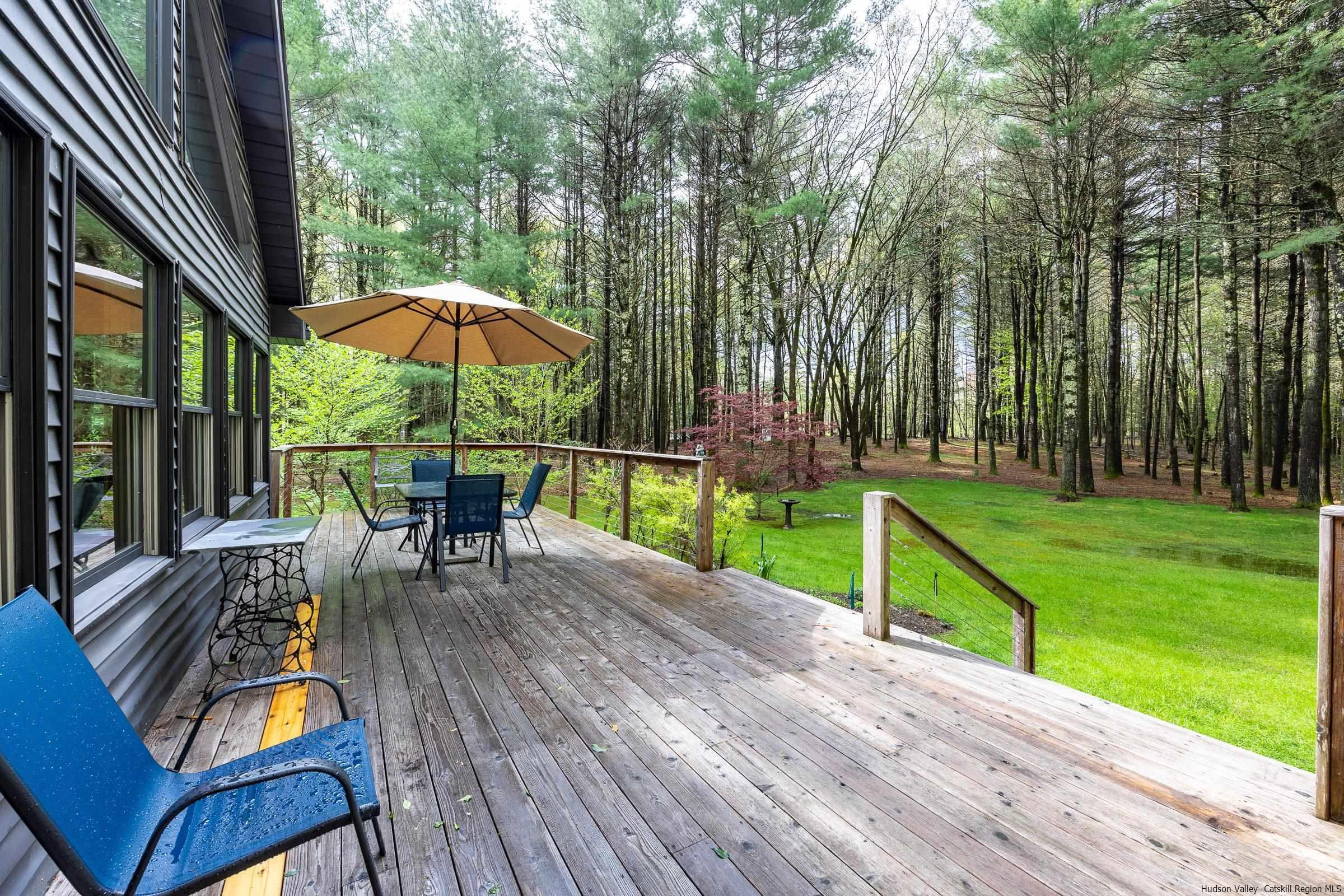 279 Scarawan Road Stone Ridge, NY 12484 - Photo 19 of 23 a view of backyard with table and chairs under an umbrella with wooden floor