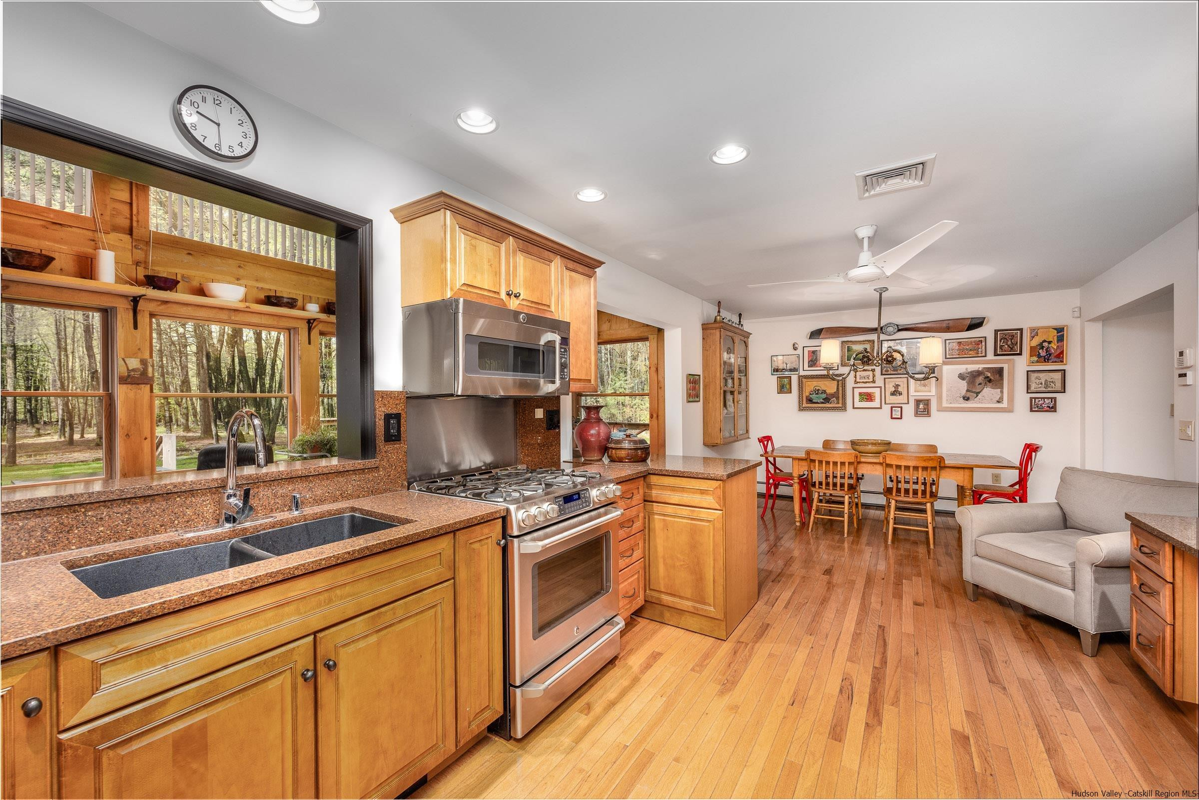279 Scarawan Road Stone Ridge, NY 12484 - Photo 9 of 23 a kitchen with stainless steel appliances a stove a sink a dining table and chairs with wooden floor