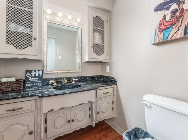 a bathroom with a granite countertop sink and a toilet