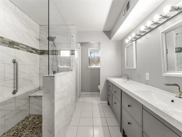 a bathroom with a double vanity sink mirror and shower