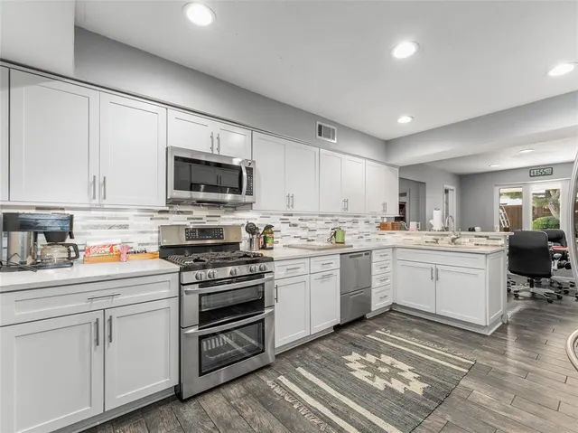 a kitchen with white cabinets appliances and a sink