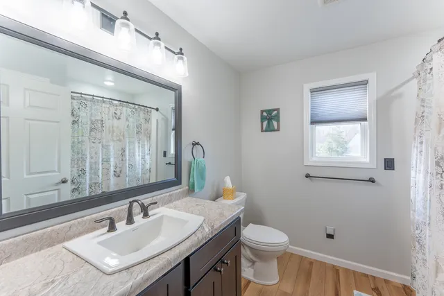 a bathroom with a toilet a sink a mirror a vanity and window