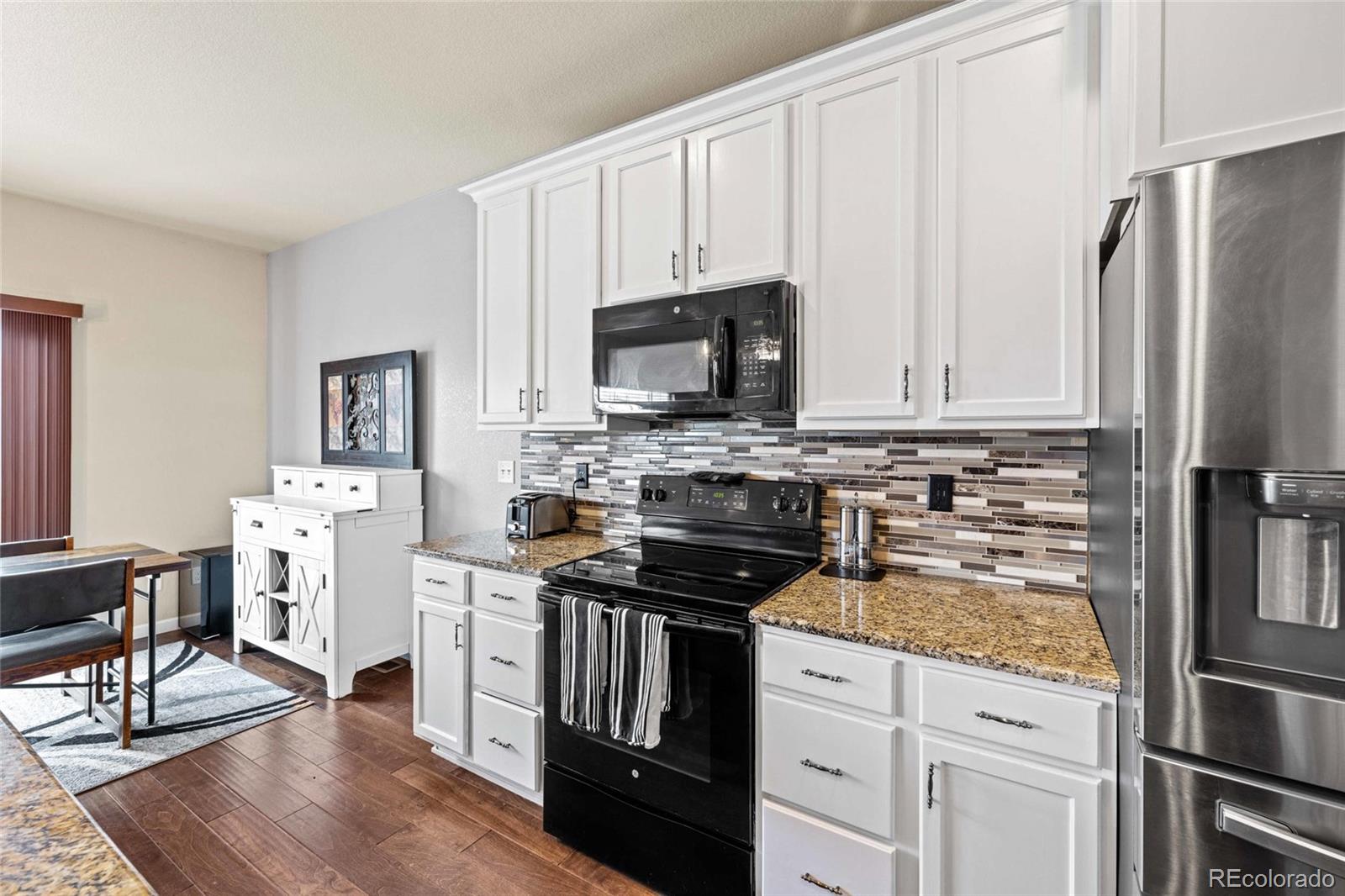 1030 Wagon Train Drive Milliken, CO 80543 - Photo 13 of 49 a kitchen with white cabinets and stainless steel appliances