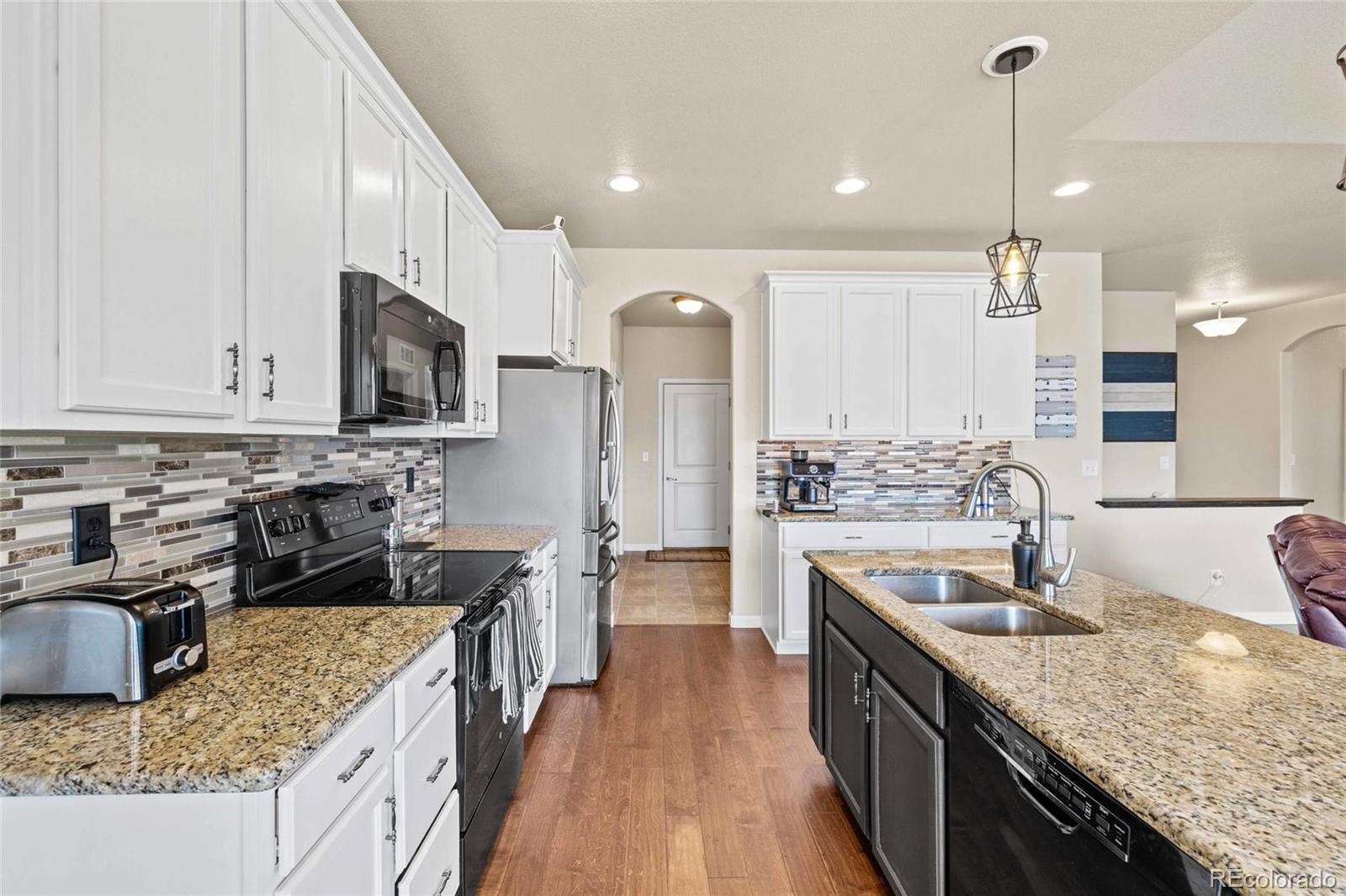1030 Wagon Train Drive Milliken, CO 80543 - Photo 15 of 49 a kitchen with stainless steel appliances granite countertop a sink stove and refrigerator