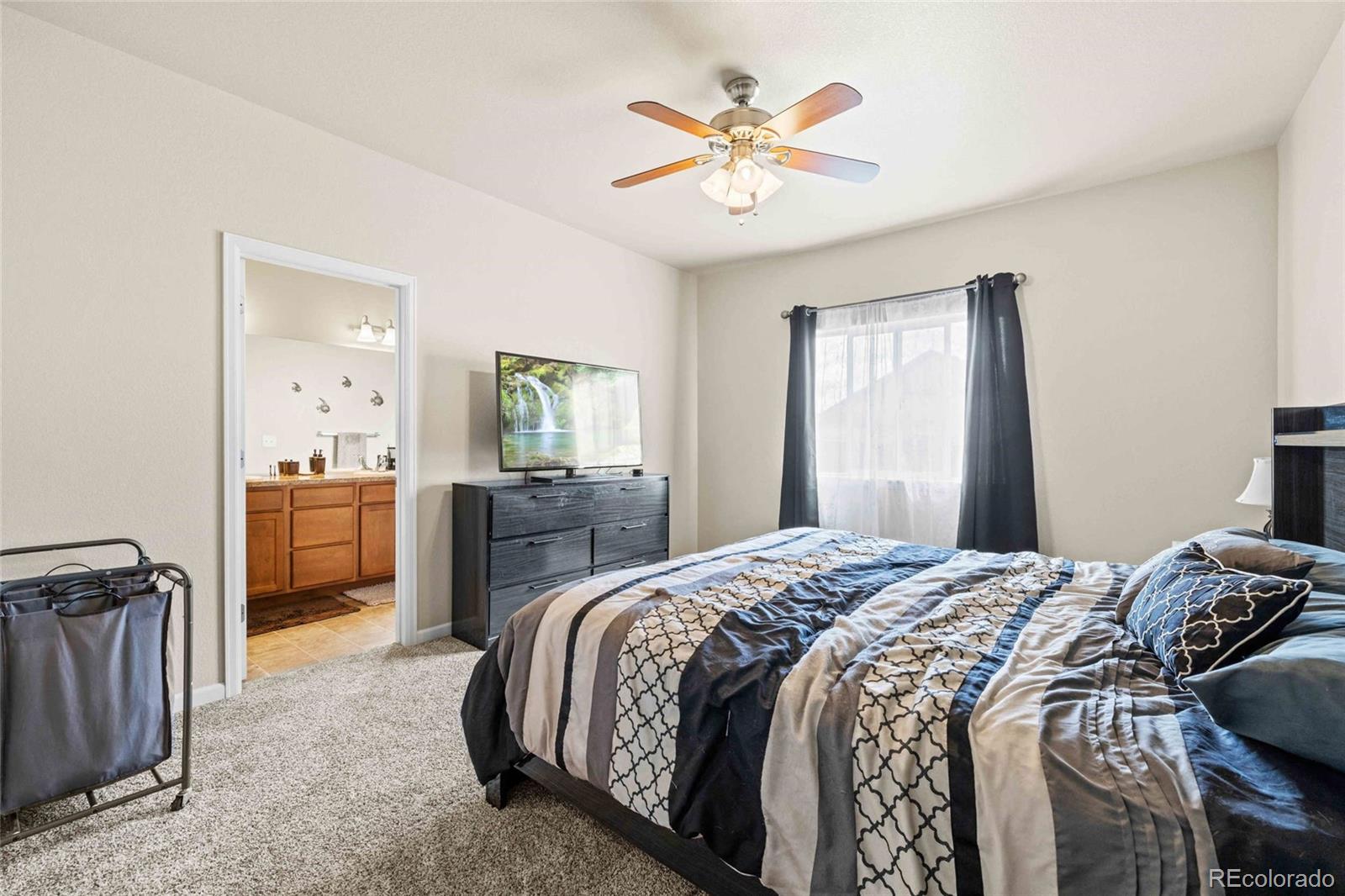 1030 Wagon Train Drive Milliken, CO 80543 - Photo 18 of 49 a bedroom with a bed and a chandelier