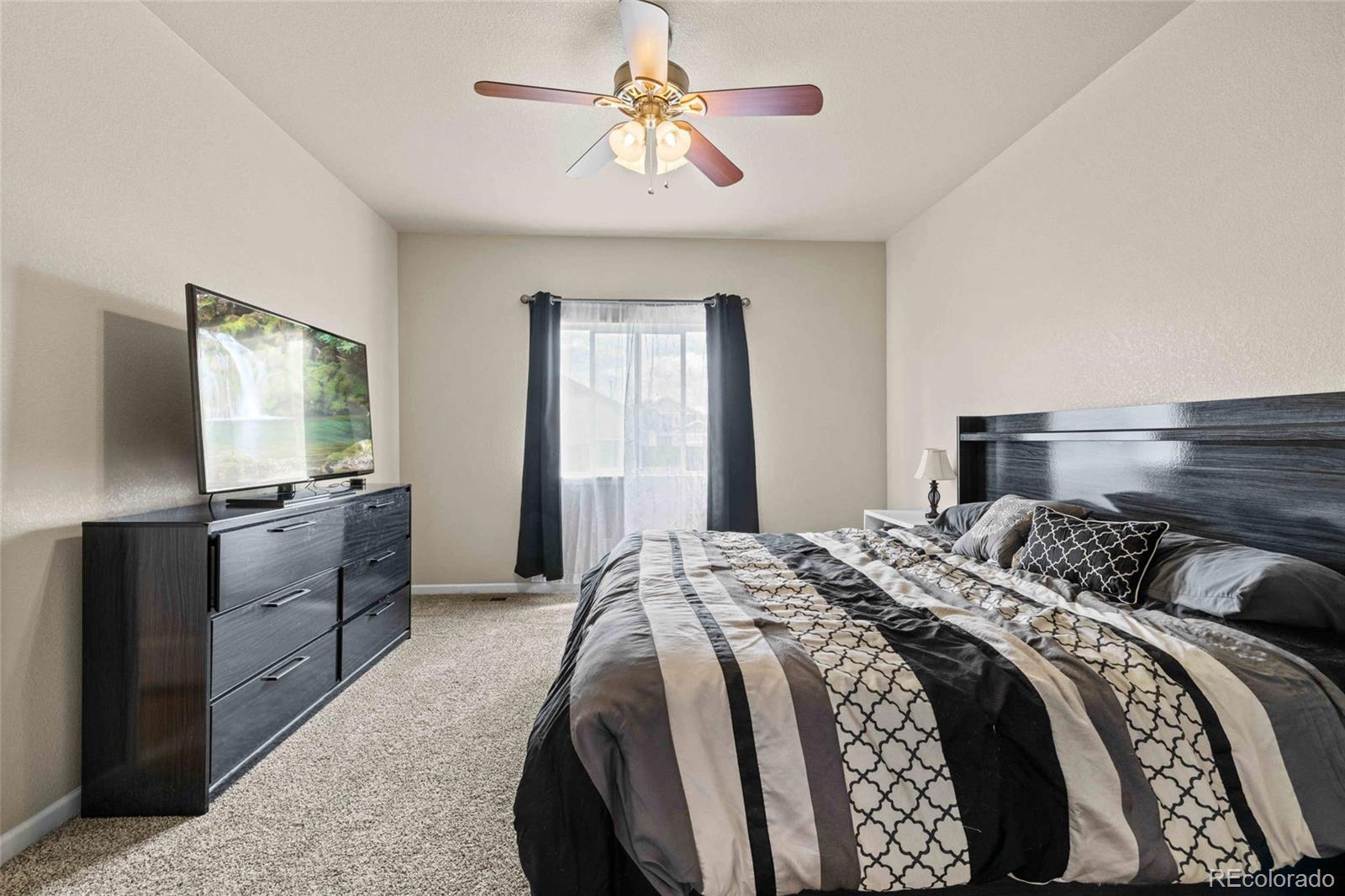 1030 Wagon Train Drive Milliken, CO 80543 - Photo 19 of 49 a bedroom with a bed and a chandelier