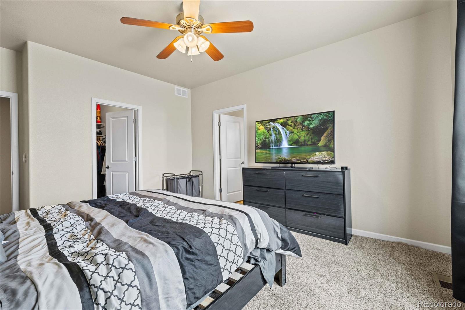 1030 Wagon Train Drive Milliken, CO 80543 - Photo 20 of 49 a bedroom with a bed and a chandelier