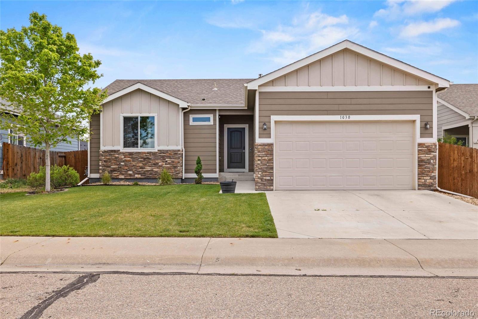 1030 Wagon Train Drive Milliken, CO 80543 - Photo 2 of 49 a front view of a house with a yard and garage