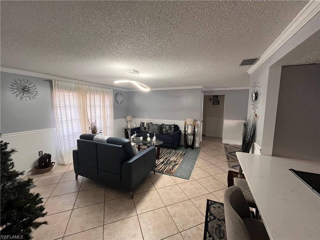 5000 17th Avenue Southwest Naples, FL 34116 - Photo 4 of 20 Tiled living room with crown molding and a textured ceiling