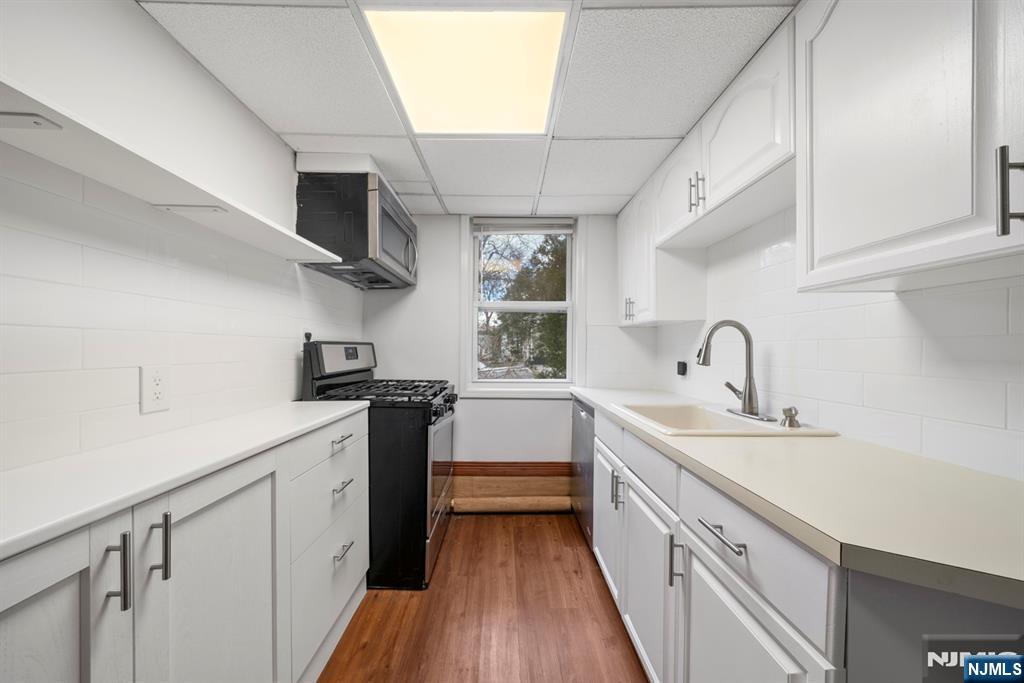 20 Columbus Avenue, Unit 2 Closter, NJ 07624 - Photo 11 of 15 a kitchen with a sink wooden floor and white stainless steel appliances