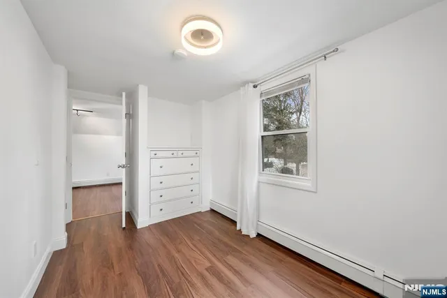 an empty room with wooden floor closet and windows
