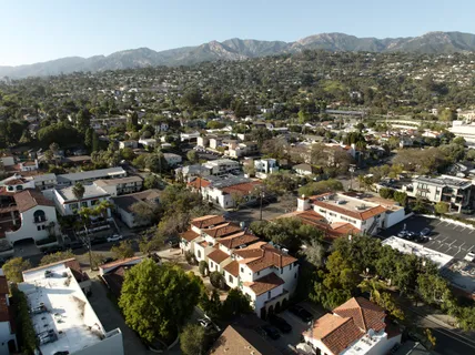 an aerial view of residential house with parking and trees