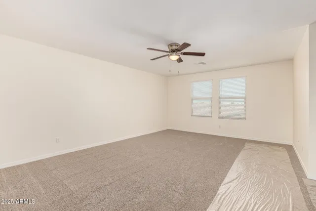 an empty room with windows and ceiling fan