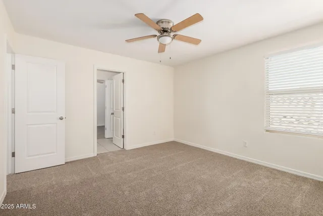 an empty room with ceiling fan and window