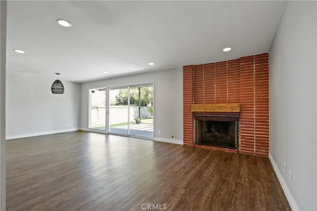an empty room with wooden floor fireplace and windows