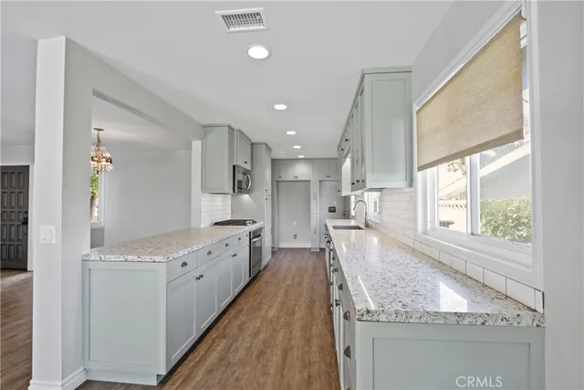 a large kitchen with granite countertop a large counter top space appliances and cabinets