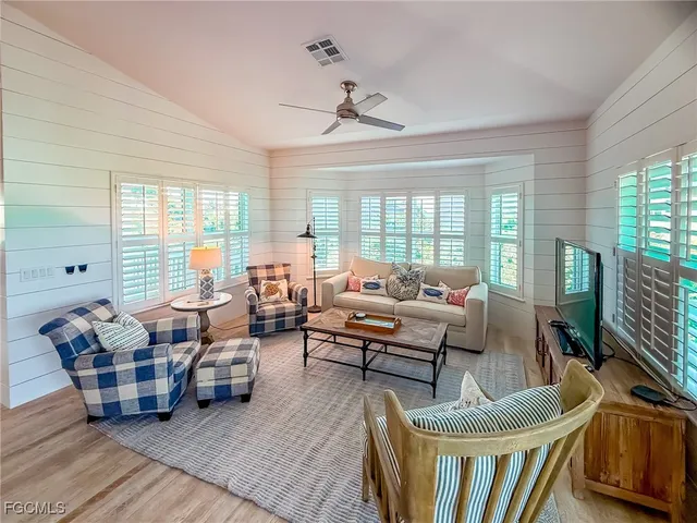 a living room with furniture floor to ceiling window and wooden floor