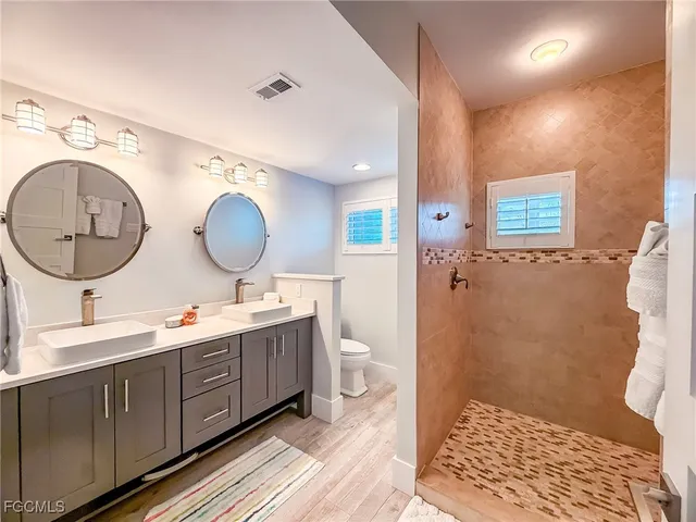 a bathroom with a double vanity sink mirror and toilet