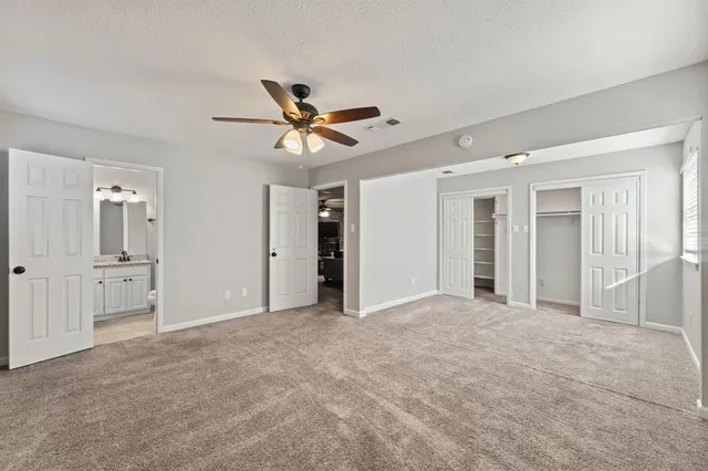 an empty room with chandelier fan and windows