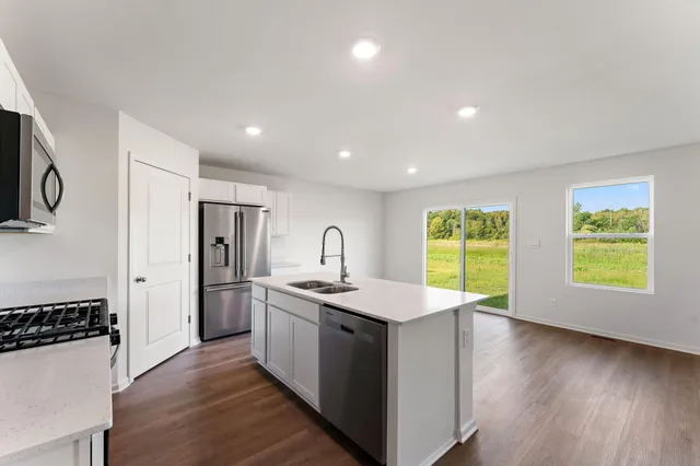 a kitchen with a sink a stove cabinets and wooden floor