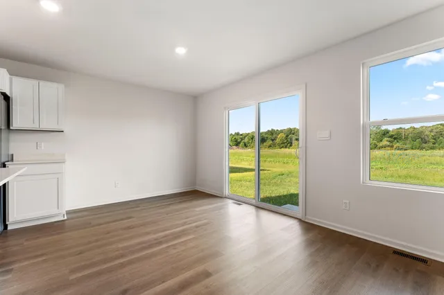 a view of an empty room with a window and wooden floor