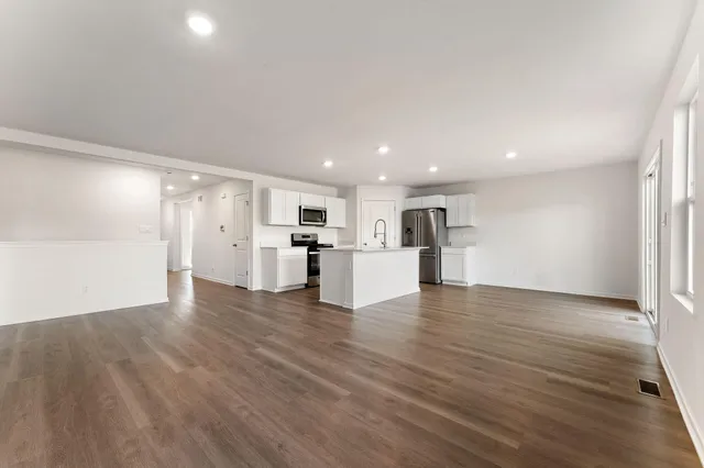 a view of a electric appliances in kitchen and empty room with wooden floor