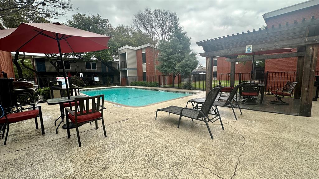 5426 Menchaca Road, Unit 125 Austin, TX 78745 - Photo 3 of 8 Swimming pool featuring a textured concrete deck, a wooden pergola, and black wrought iron fencing