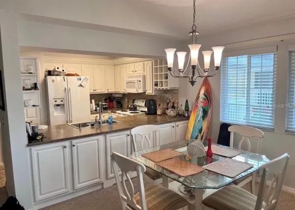 a view of a dining room and livingroom with furniture wooden floor a chandelier
