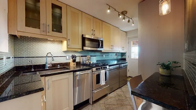 a kitchen with stainless steel appliances granite countertop a sink a stove and cabinets