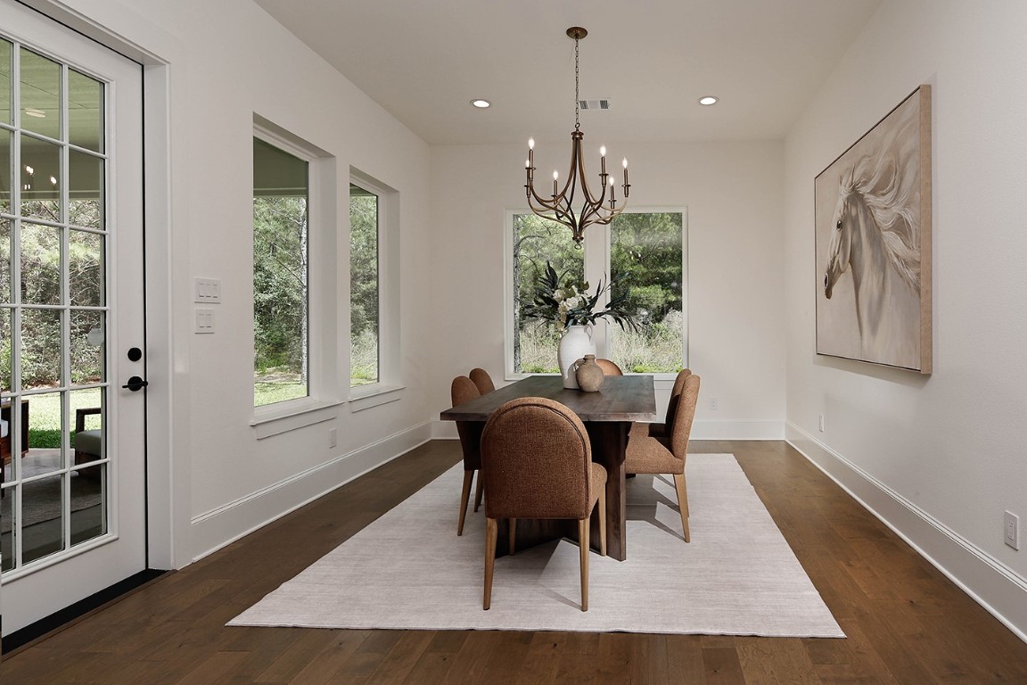 11709 Grand N Road Willis, TX 77378 - Photo 17 of 37 Dining room is surrounded by windows with pleasant, serene views to lovely backyard/lanai. French oak wood flooring and modern chandelier lend to the sophisticated ambiance.