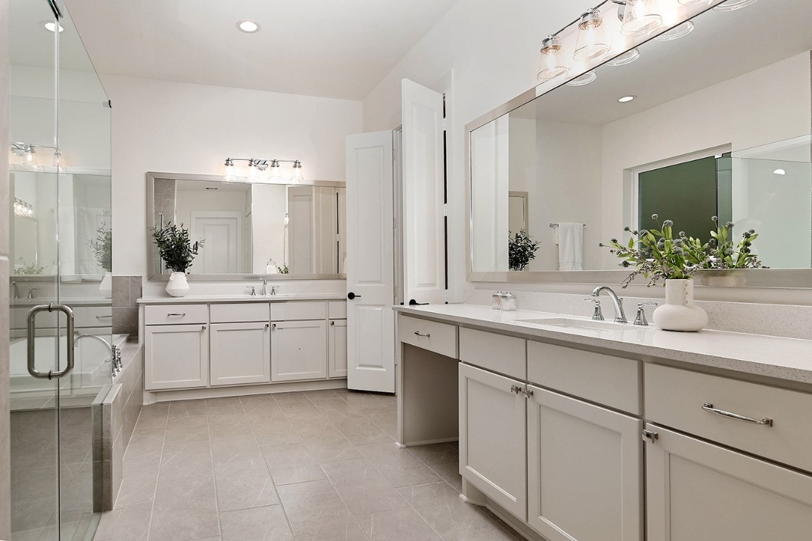 11709 Grand N Road Willis, TX 77378 - Photo 21 of 37 Primary ensuite is well-designed with dual vanity areas, soaking tub and walk-in shower with bench and frameless glass enclosure.