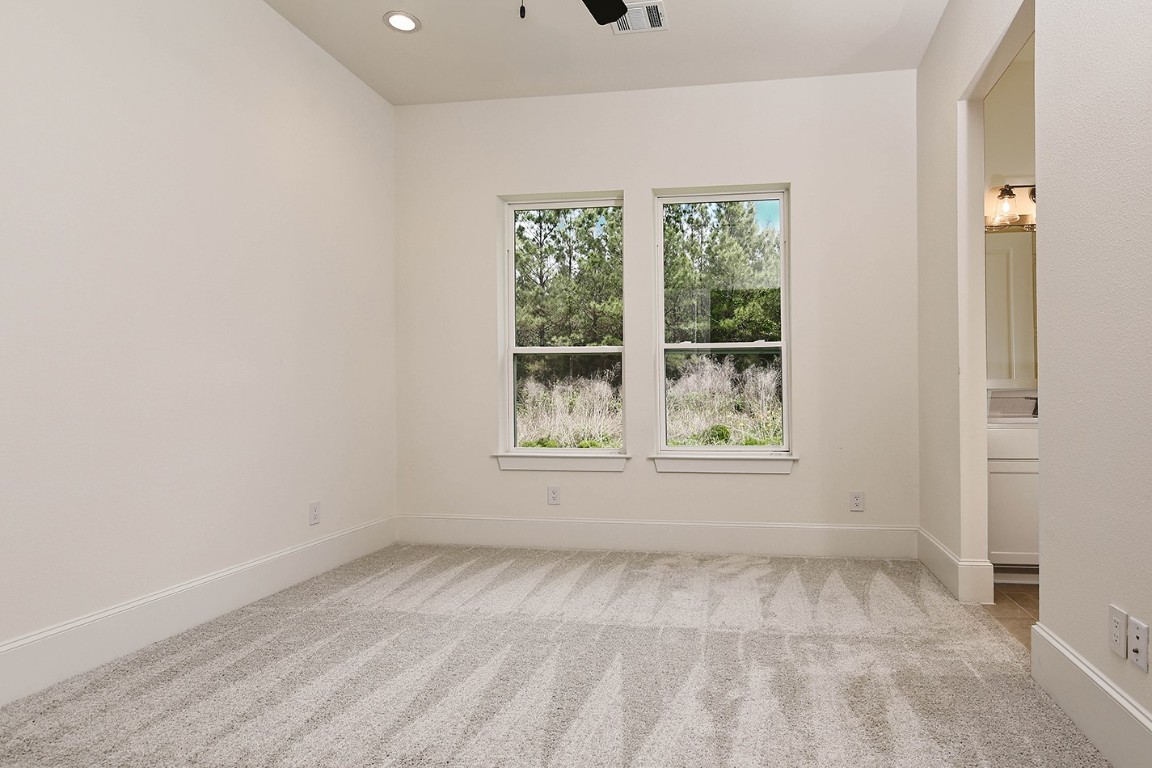 11709 Grand N Road Willis, TX 77378 - Photo 24 of 37 Bedroom 2 has soft neutral color palette, black modern fan, and ample natural light with views. Ensuite bath has separate vanity area for each bedroom with adjoining tub/shower/toilet area.