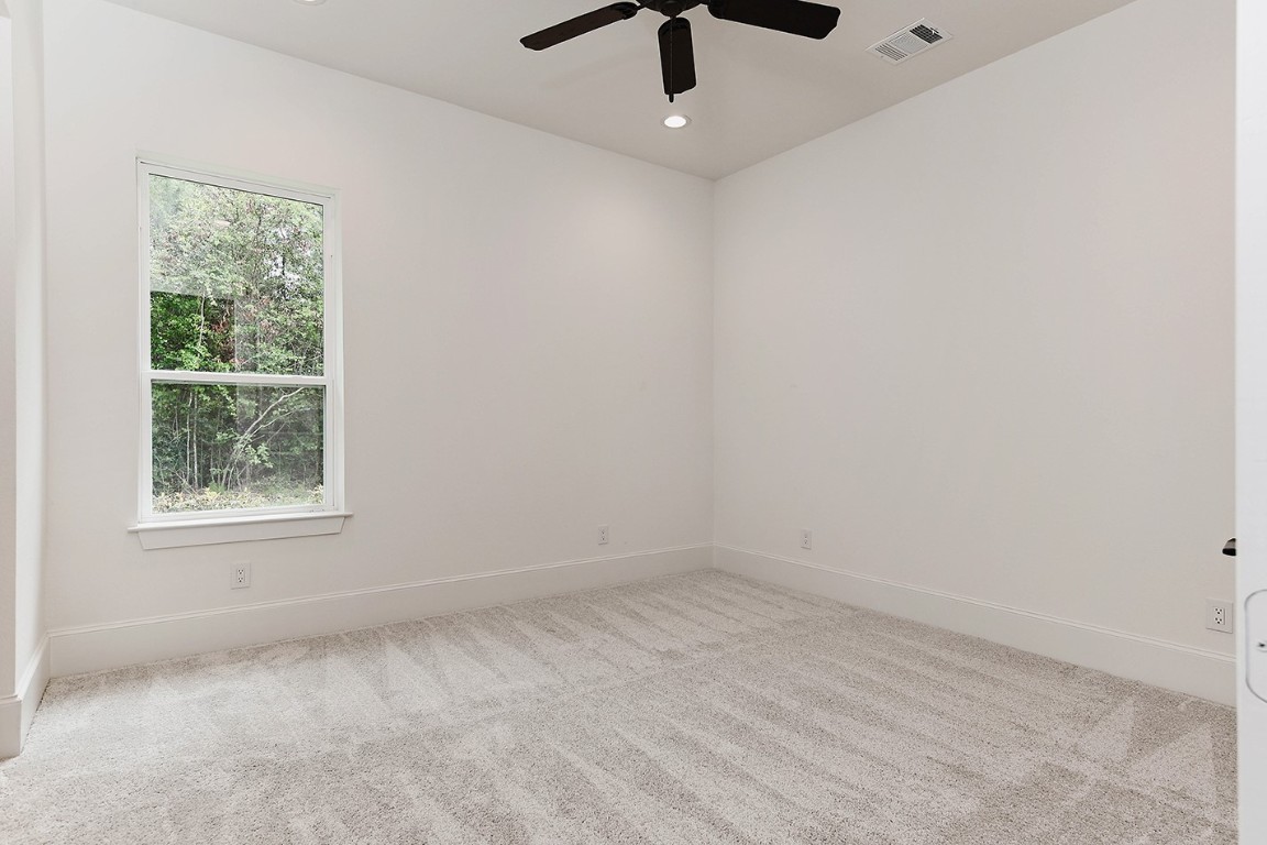 11709 Grand N Road Willis, TX 77378 - Photo 27 of 37 Bedroom 3 has pleasing neutral colors, modern black ceiling fan, great outdoor views and ensuite bath shared by bedroom 2.