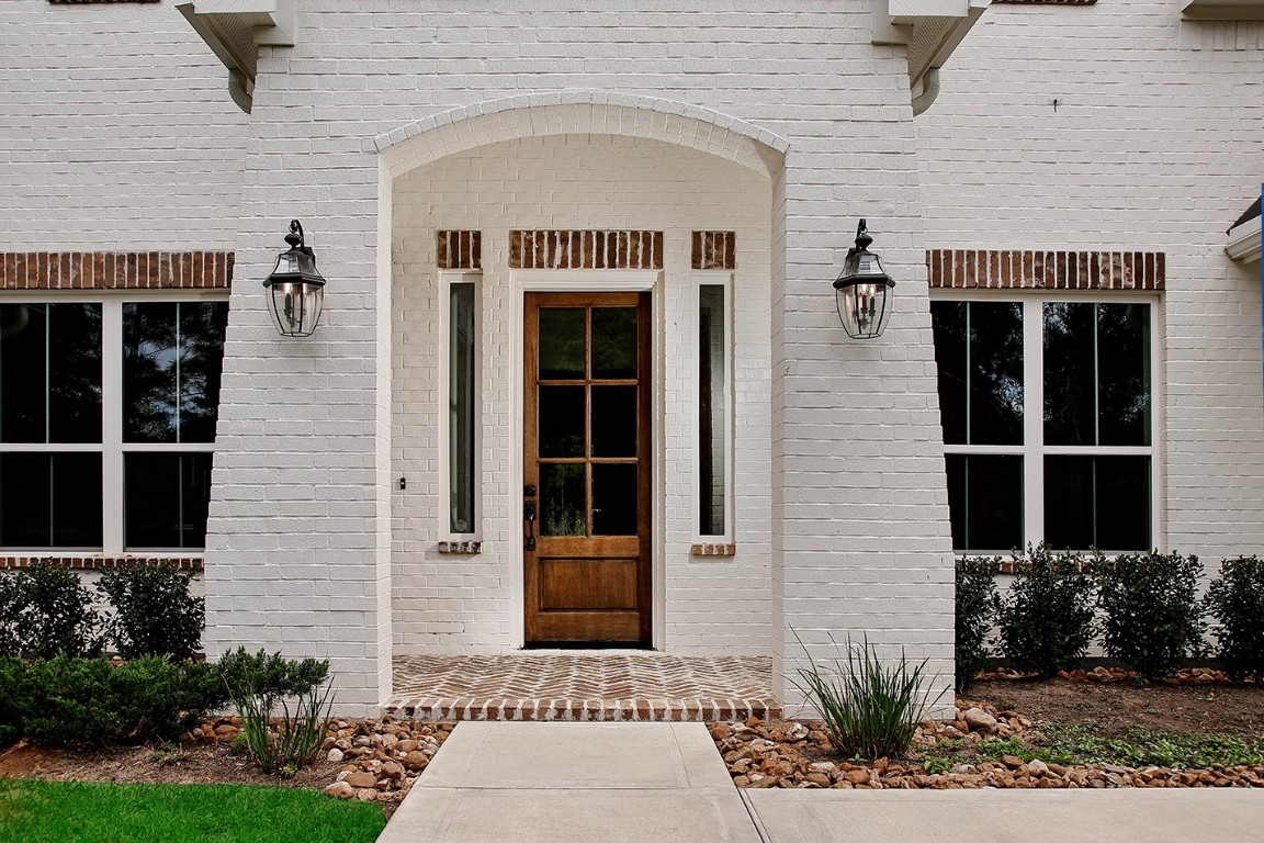 11709 Grand N Road Willis, TX 77378 - Photo 3 of 37 Pristine architectural details highlight front entrance with arched white brick opening, accented by antique brick on window headers/sills, porch decking, and the rich-wood stained custom door with 6-lites welcomes you inside.