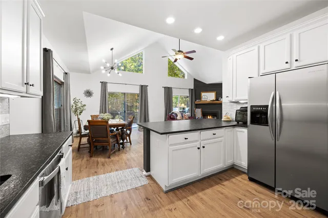 a kitchen with granite countertop a refrigerator a stove a dining table and chairs with wooden floor