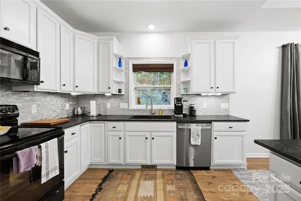 a kitchen with stainless steel appliances granite countertop a stove a sink and a microwave