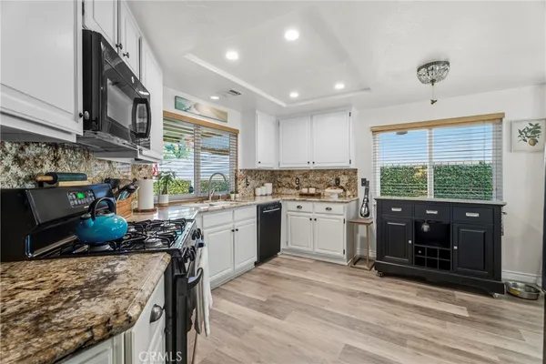 a kitchen with stainless steel appliances granite countertop a stove a sink dishwasher a microwave oven and a refrigerator with wooden cabinets