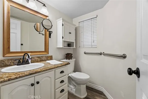a bathroom with a granite countertop sink a toilet and a mirror