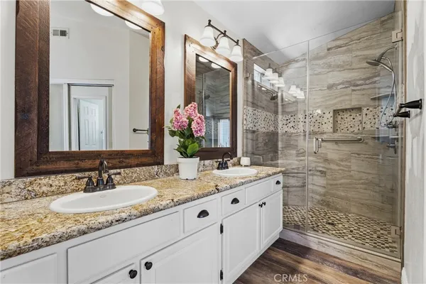 a bathroom with a granite countertop sink a mirror and a shower
