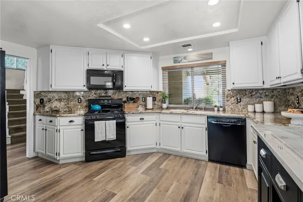 a kitchen with granite countertop a sink cabinets stainless steel appliances and a window
