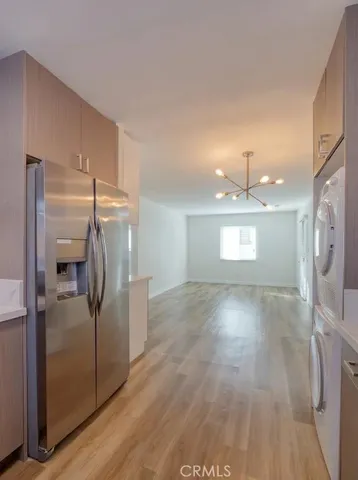 a view of a refrigerator in kitchen and an empty room