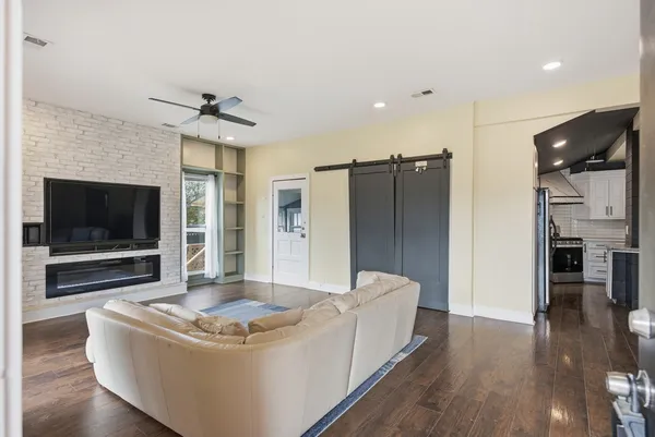 a living room with stainless steel appliances furniture a flat screen tv and a fireplace