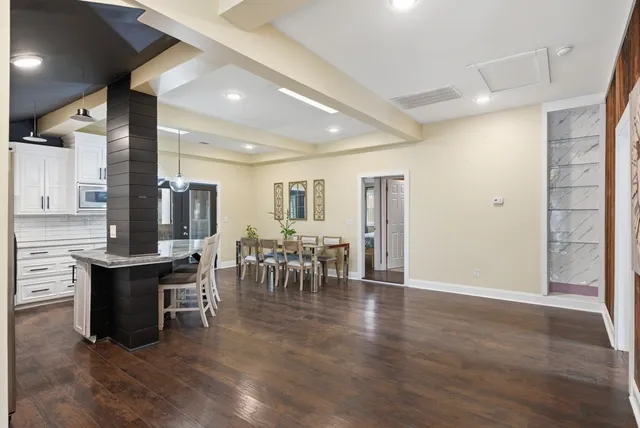 a dining hall with stainless steel appliances granite countertop a table chairs and a sink