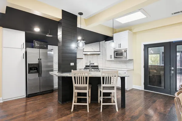 a kitchen with stainless steel appliances kitchen island granite countertop a table chairs sink and cabinets