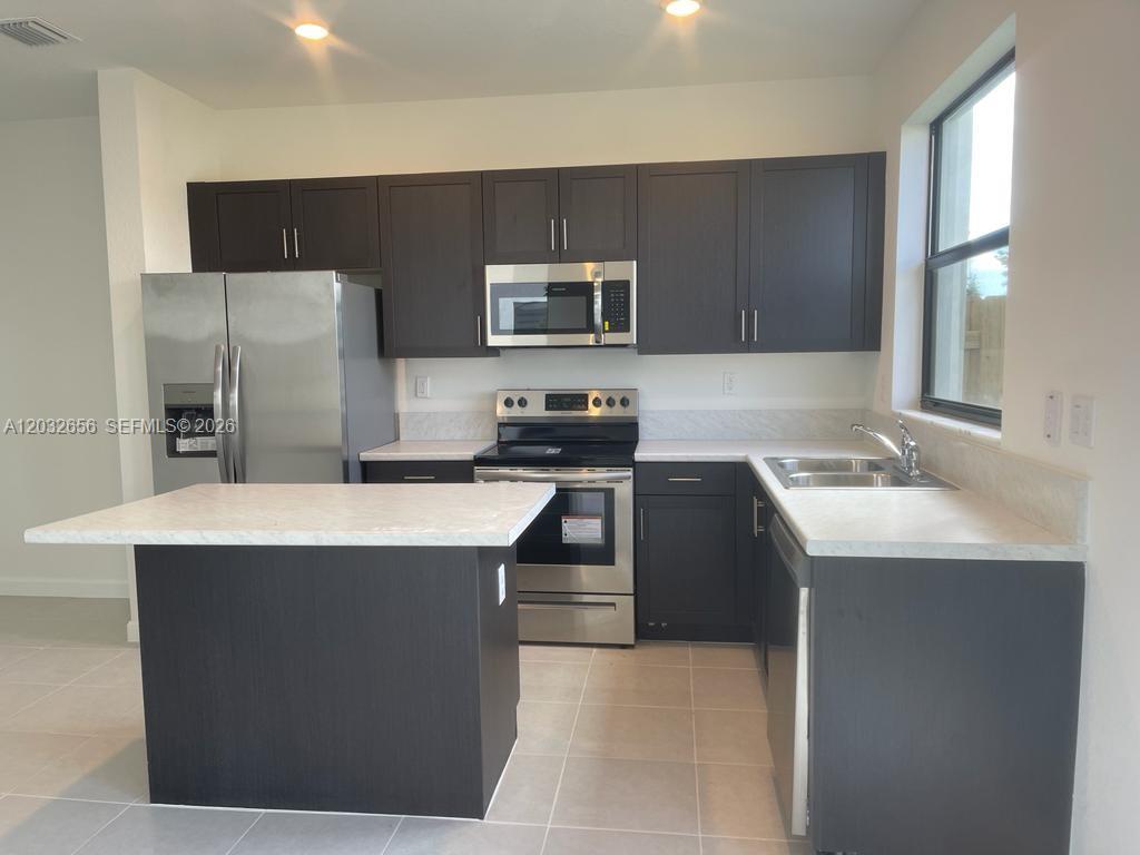 10144 Southwest 228th Terrace Miami, FL 33190 - Photo 9 of 23 a kitchen with stainless steel appliances a stove a sink a refrigerator and a refrigerator