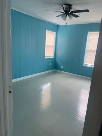 an empty room with windows and fan
